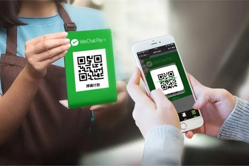 Person scans a QR code for WeChat Pay using a smartphone at checkout